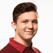 a young man wearing a red shirt with a red collar smiles for the camera