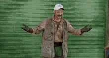 a man is standing in front of a green garage door with his arms outstretched and the word yes on the screen .