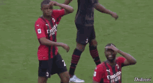 a soccer player wearing a red and black jersey with emirates fly better on it is standing on a field .