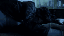 a person in a leather jacket is laying on the floor in a dark room