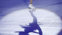 a woman is ice skating on a rink and her shadow is cast on the ice .