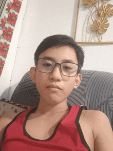 a young boy wearing glasses and a red tank top