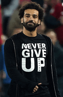 a man with a beard wears a black shirt that says never give up