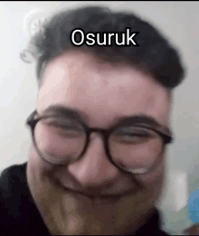 a man with glasses and a beard is smiling with the word osuruk written on his face