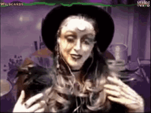 a woman in a witch costume is wearing a black hat and headphones .