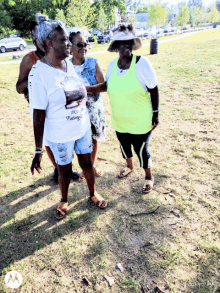 three women are standing in a grassy field and one of them is wearing a shirt that says " freedom "