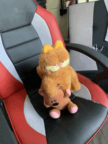 a stuffed cat and a teddy bear are sitting on a red and black chair