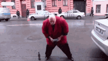 a man in a red coat is standing in front of a silver car with license plate p 2099 78