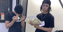 two men are standing next to each other holding a fan of money .