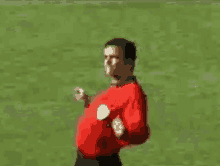 a man in a red shirt is walking on a field