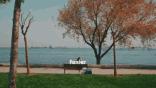 a woman sits on a bench in front of a body of water with the word fanlar written above her