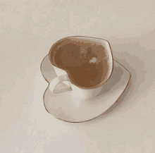 a cup of coffee with a heart shaped handle on a saucer