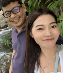 a man and a woman are posing for a picture with the woman wearing a necklace with the letter h on it