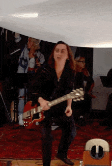 a man with long hair is playing a guitar in a room