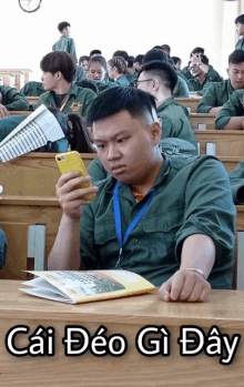 a man sitting in a lecture hall looking at his phone with the words cai deo gi day written below him