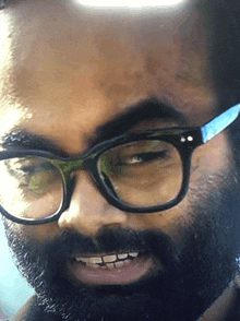 a man with glasses and a beard is smiling with his eyes closed