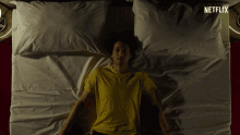 a man in a yellow shirt is laying on a bed with netflix written on the bottom