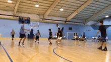 a group of boys are playing basketball in a gym and the scoreboard shows that the game is tied at the half