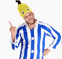 a man wearing a blue and white striped shirt and a yellow hat points upwards