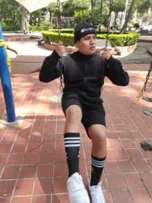 a man wearing a champion beanie is sitting on a swing