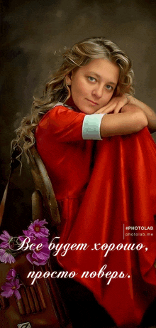 a woman in a red dress sits in a chair with purple flowers in front of her