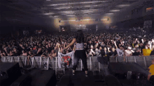 a woman stands in front of a crowd at a concert holding a flag that says ' very ugly '