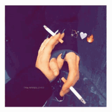 a person is holding two cigarettes in their hands with hearts and a fire coming out of them .