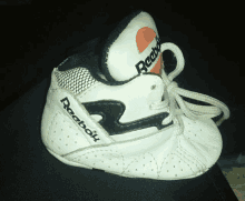 a baby 's white and black reebok shoe is sitting on a black surface