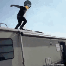 a person wearing a helmet and goggles is jumping off the roof of a trailer .