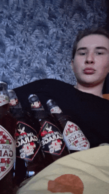 a man is laying on a bed with three bottles of cherry juice in front of him