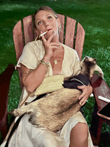 a woman smoking a cigarette while holding a goat in her lap