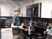 a boy in a kitchen with a box of caramelli on the stove top