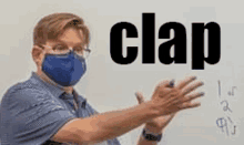 a man wearing a mask is clapping his hands in front of a whiteboard with the word clap written on it .