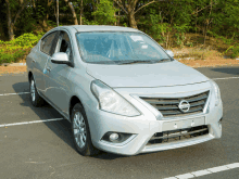 a silver nissan car is parked on the side of the road