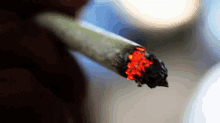 a close up of a person smoking a cigarette with red smoke coming out of it