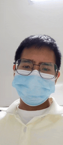 a man wearing glasses and a blue mask looks at the camera