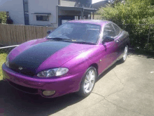 a purple car with black stripes on the hood is parked in a driveway