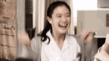 a woman in a white lab coat is laughing with her hands in the air .