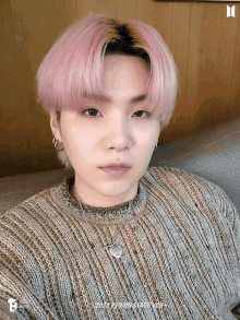 a man with pink hair is wearing a sweater and a necklace