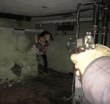 a person is pointing a gun at a stuffed mickey mouse doll in a dark room .