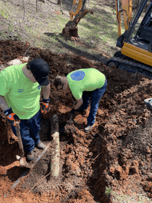 two men are digging in the dirt and one of them is wearing a shirt that says ' mobile home maintenance ' on it