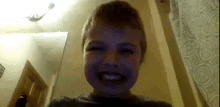 a young boy is smiling at the camera in a dark room