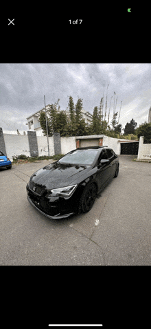 a black car is parked in a parking lot with the number 1 of 7 on the bottom left