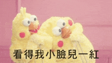 two stuffed chickens are standing next to each other on a pink background with chinese writing .