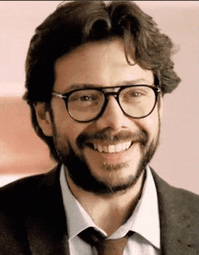 a man with a beard wearing glasses and a tie is smiling .