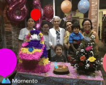 a group of people are posing for a picture in front of a cake and balloons and the word momento is on the bottom