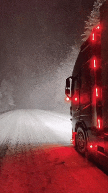 a truck is driving down a snowy road with red lights