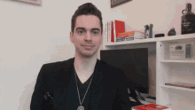 a man stands in front of a desk with books on it and a bottle of absolut vodka on the shelf