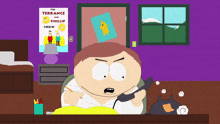 a poster for the terrance and phillip show hangs above a man sitting at a desk