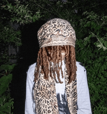 a person with dreadlocks wearing a leopard print scarf around their neck